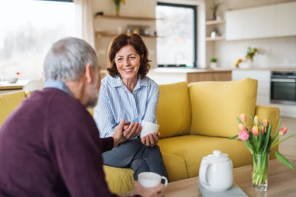 Una cariñosa pareja de ancianos enamorados sentados en el sofá en casa . — Foto de Stock