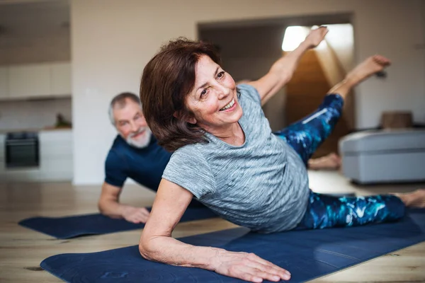 Ett Senior par inomhus hemma, gör övning på golvet. — Stockfoto