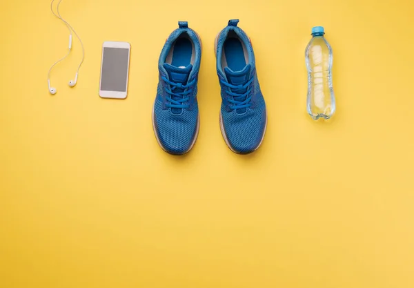 Uma foto de estúdio de tênis de corrida e smartphone em fundo amarelo. Depósito plano . — Fotografia de Stock