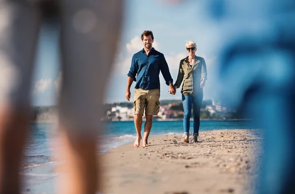 Young couple walking outdoors on beach, holding hands. — Stock Photo, Image