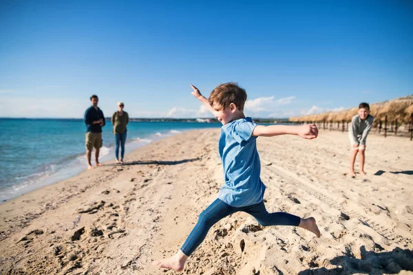 Ein kleines Mädchen mit Familie läuft draußen am Sandstrand und hat Spaß. — Stockfoto
