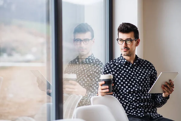 Kahve ve tabletle pencerenin yanında oturan genç adam. Boşluğu kopyala. — Stok fotoğraf