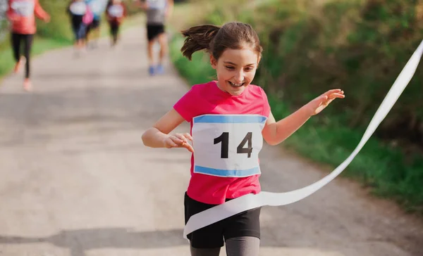 Pequeña corredora cruzando la línea de meta en una competición de carreras en la naturaleza . — Foto de Stock