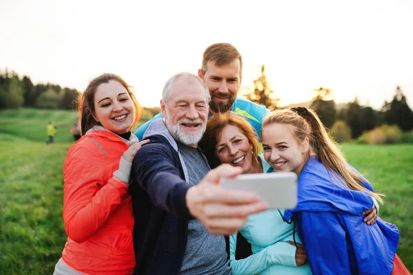 Um grupo de pessoas aptas e ativas descansando depois de fazer exercício na natureza, tomando selfie . — Fotografia de Stock