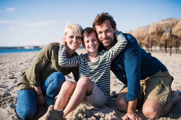 Young family with small boy sitting outdoors on beach, looking at camera. — 스톡 사진