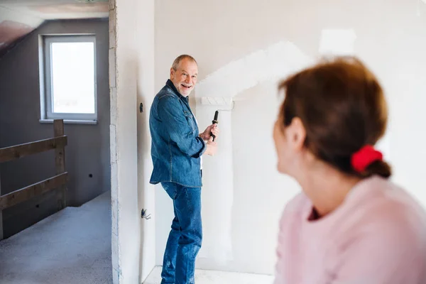 Couple sénior peignant des murs dans une nouvelle maison, concept de déménagement . — Photo