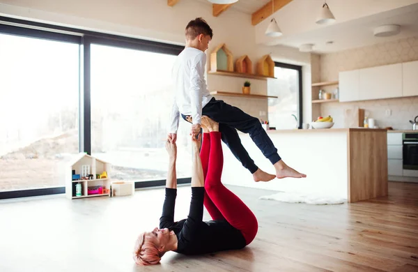 Una joven con un hijo pequeño jugando en el suelo, divirtiéndose . — Foto de Stock