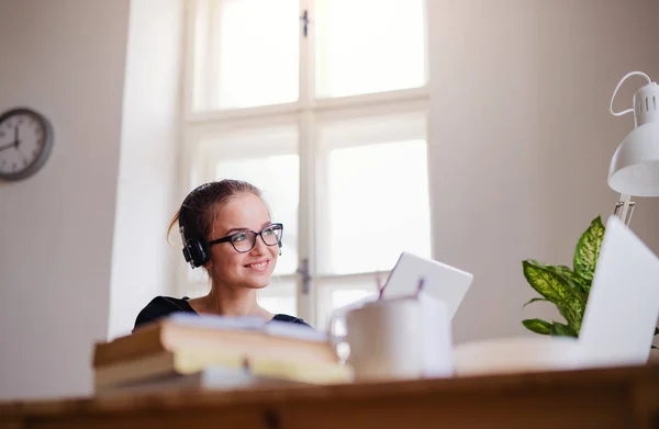 Una joven estudiante sentada en la mesa, usando auriculares al estudiar . —  Fotos de Stock