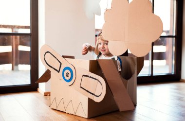 Karton uçak ile bir bebek çocuk evde kapalı oynarken, uçan kavram.