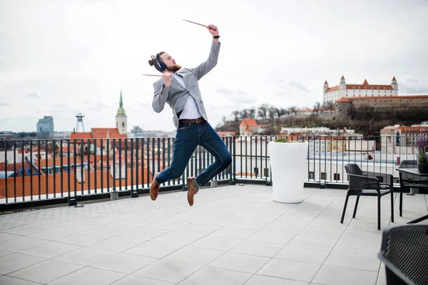 Un giovane uomo d'affari con le cuffie in piedi su una terrazza, divertirsi . — Foto Stock