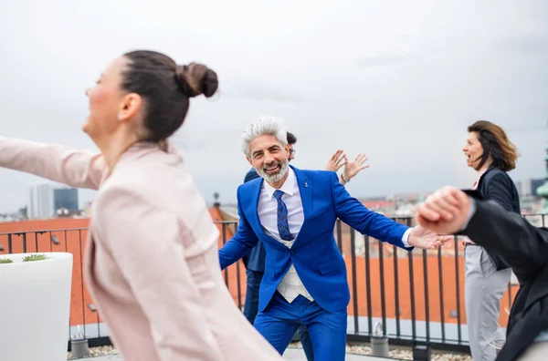 Un gruppo di uomini d'affari gioiosi che fanno una festa all'aperto sulla terrazza sul tetto della città, ballando . — Foto Stock