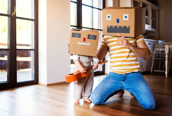 Una niña con padre jugando con un monstruo de cartón en casa . —  Fotos de Stock