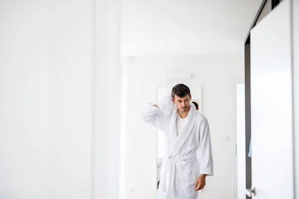 Hombre joven con albornoz en el dormitorio, una rutina de la mañana . —  Fotos de Stock