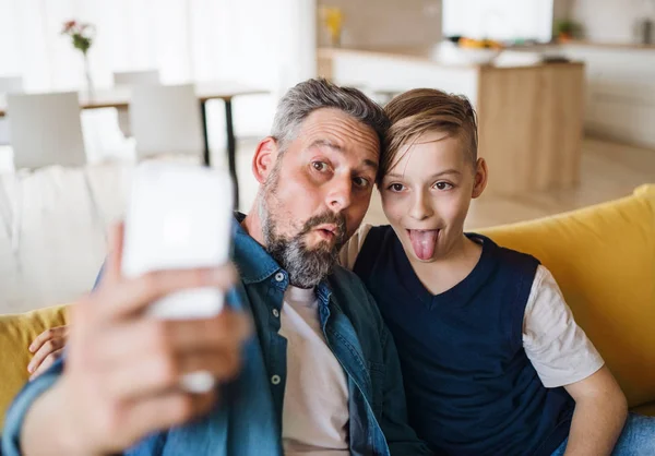 Ayah dengan anak kecil duduk di sofa di dalam ruangan, Berduka ketika mengambil selfie . — Stok Foto