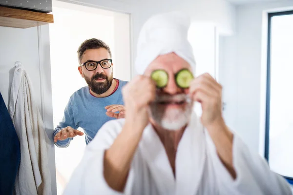 Un hijo hipster adulto y padre mayor en el baño en casa, divirtiéndose . — Foto de Stock