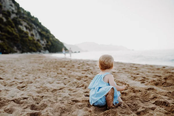 Een kleine peuter meisje spelen in zand op strand op zomervakantie. — Stockfoto