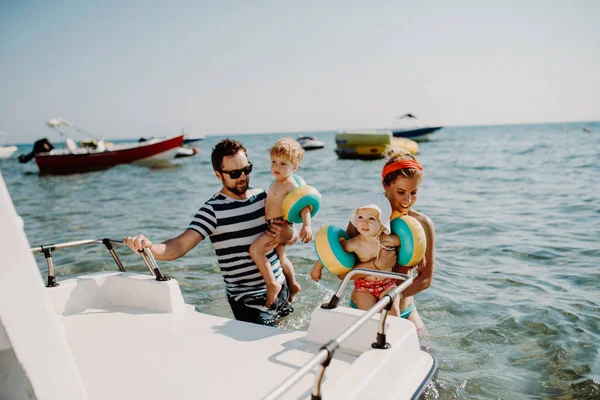 Pais com duas crianças pequenas em pé de barco nas férias de verão . — Fotografia de Stock