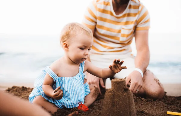 Pai com uma menina brincando na praia nas férias de verão . — Fotografia de Stock