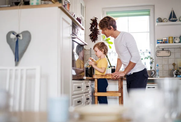 Un padre joven con un hijo pequeño en una cocina en casa . —  Fotos de Stock