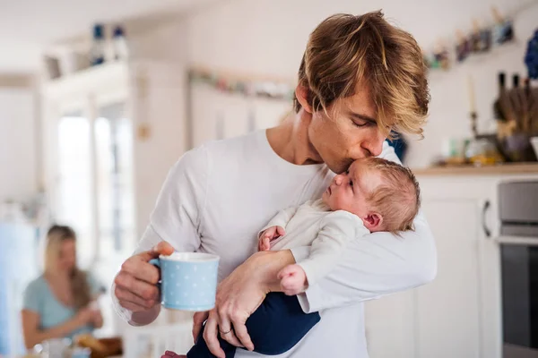 若いお父さん家で台所で新生児を持っている、キス. — ストック写真