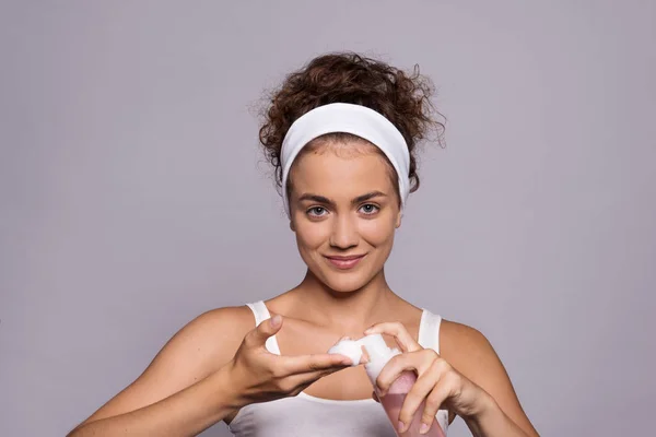 Retrato de una joven limpiando la cara en un estudio, belleza y cuidado de la piel . — Foto de Stock