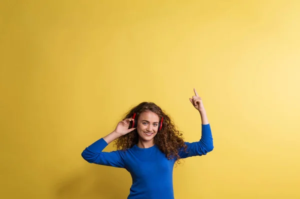 Портрет молодой женщины с наушниками в студии на желтом фоне . — стоковое фото