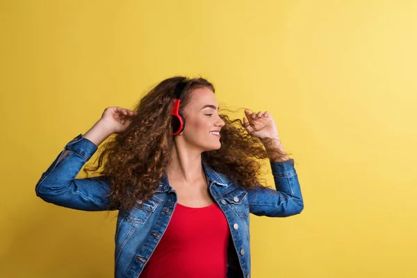 Портрет молодої жінки з навушниками в студії на жовтому фоні . — стокове фото