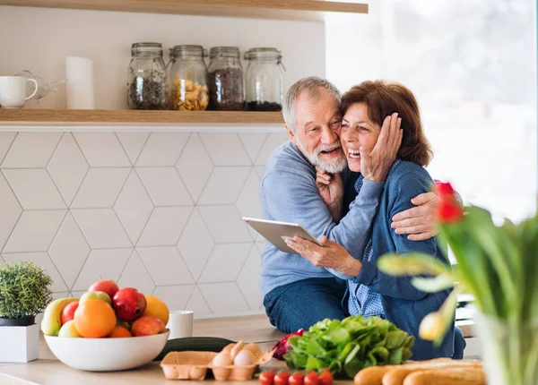 Ett porträtt av Senior par kär inomhus hemma, med hjälp av Tablet. — Stockfoto