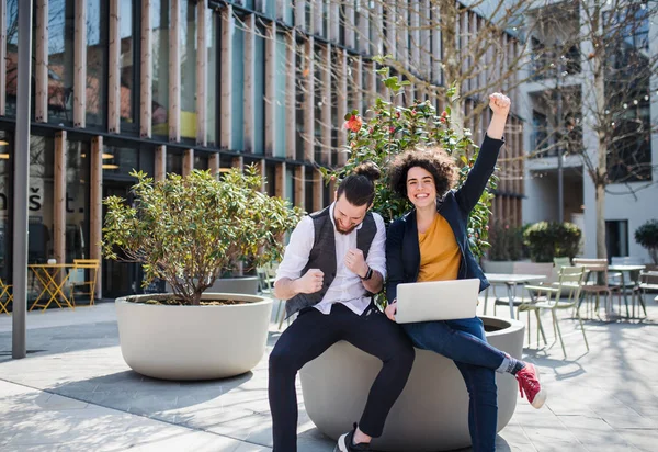 Junge Geschäftsleute mit Laptop draußen im Hof und drücken ihre Begeisterung aus. — Stockfoto