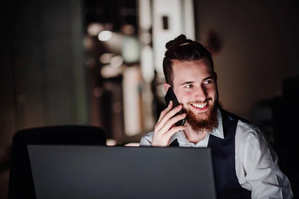Een portret van de jonge zakenman met computer en smartphone in een kantoor. — Stockfoto