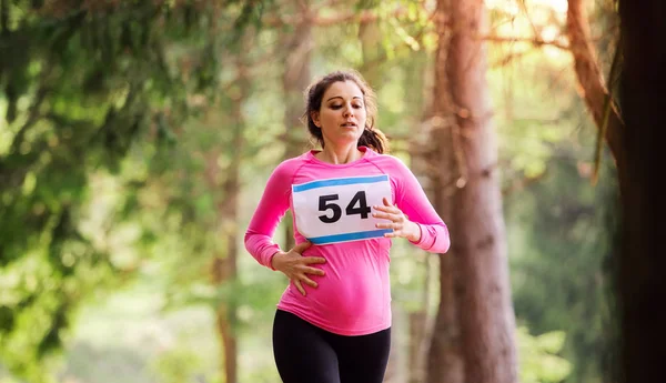 Mujer embarazada corriendo una competición de carreras en la naturaleza . —  Fotos de Stock