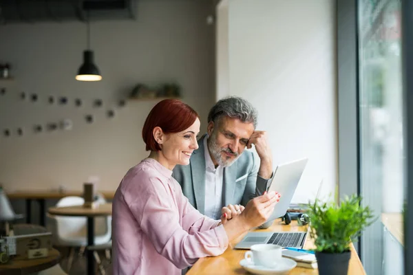 Homme et femme ayant une réunion d'affaires dans un café, en utilisant un ordinateur portable . — Photo