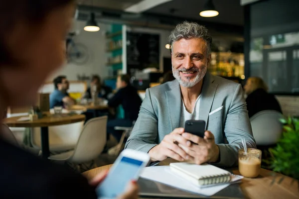 Mann und Frau bei einem Geschäftstreffen in einem Café, mit Smartphones. — Stockfoto