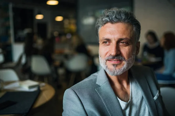 Een portret van een volwassen zakenman die in een café zit. Ruimte kopiëren. — Stockfoto