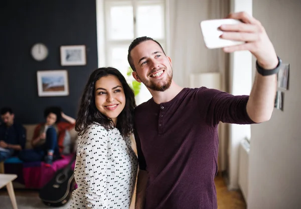 Um grupo de jovens amigos com smartphone dentro de casa, levando selfie . — Fotografia de Stock