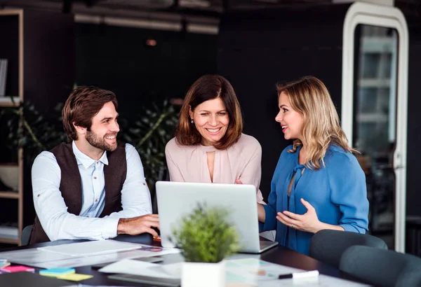 A group of business people sitting in an office, using laptop. — Stock Photo, Image