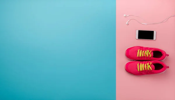 Una toma de estudio de zapatillas y teléfonos inteligentes en el fondo de color. Puesta plana . — Foto de Stock