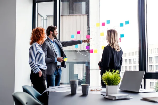 A group of young business people in an office, brainstorming. — Stock Photo, Image