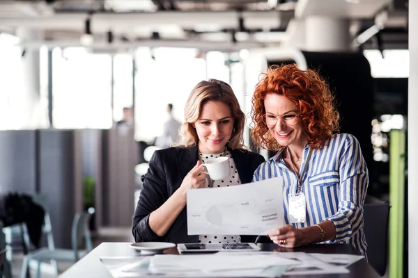 Two female business people sitting in an office, talking. — Stock Photo, Image