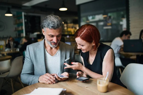 Mann und Frau bei einem Geschäftstreffen in einem Café mit Smartphone. — Stockfoto