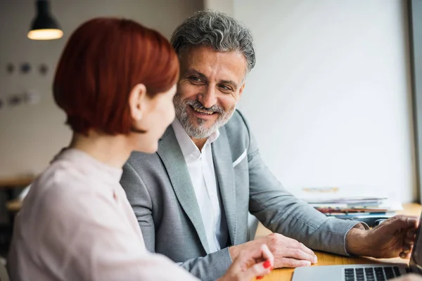 Hombre y mujer teniendo una reunión de negocios en un café, utilizando el ordenador portátil . — Foto de Stock