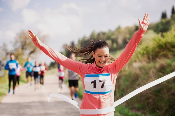 Jonge vrouw runner Crossing finishlijn in een racecompetitie in de natuur. — Stockfoto
