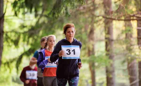 Gran grupo de personas de varias generaciones corriendo una competición de carreras en la naturaleza . — Foto de Stock