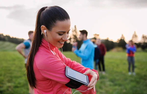 Eine junge Frau mit einer Gruppe von Menschen, die in der Natur Sport treiben, sich ausruhen. — Stockfoto