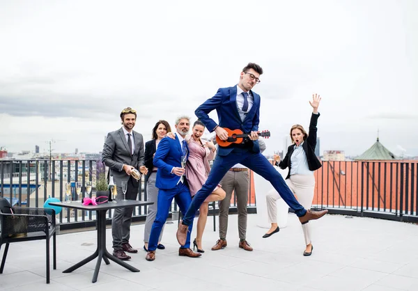 Группа веселых бизнесменов, проводящих вечеринку на открытом воздухе на террасе на крыше в городе . — стоковое фото