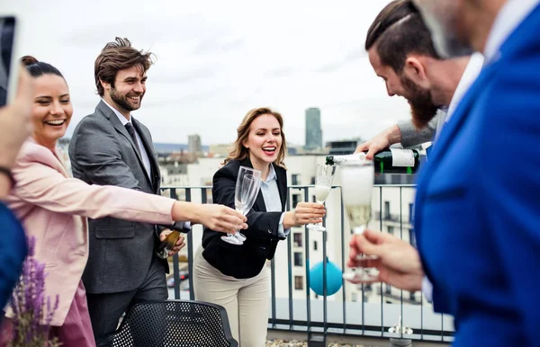 Un groupe d'hommes d'affaires joyeux faisant une fête à l'extérieur sur la terrasse du toit en ville . — Photo