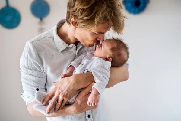 Een jonge vader houdt een pasgeboren baby thuis, zoenen. — Stockfoto