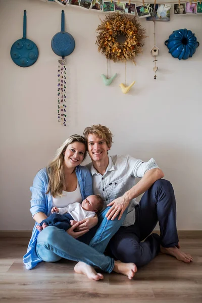 Un ritratto di bei giovani genitori con un neonato a casa . — Foto Stock