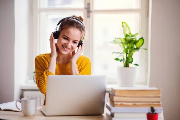 Una joven estudiante sentada en la mesa, usando un portátil cuando estudia . — Foto de Stock