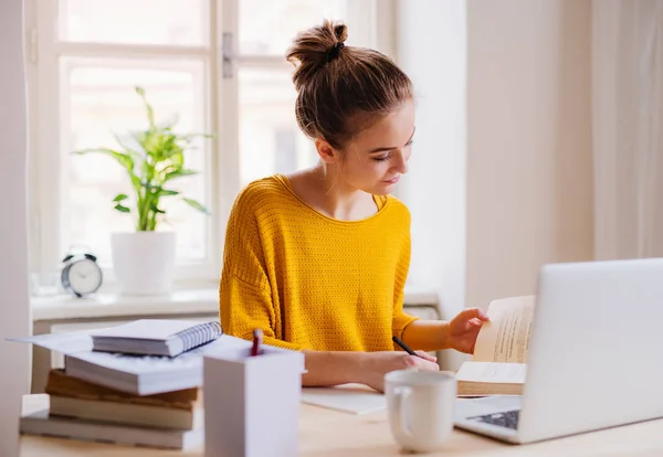 O tânără studentă care stă la masă, folosind laptopul atunci când studiază . — Fotografie, imagine de stoc